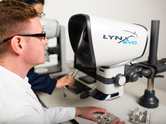 Lynx EVO stereo zoom microscope operated by man with glasses in white coat